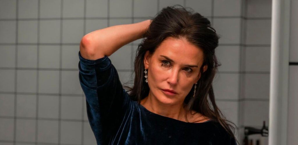 In this still photo from THE SUBSTANCE movie, screening at Toronto International Film Festival, actress, Demi Moore looks at her reflection in the mirror with smeared mascara around her left eye.